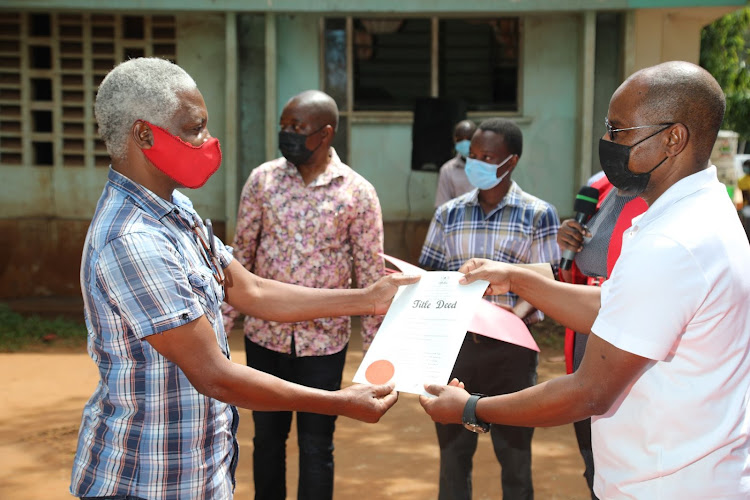 Kilifi Governor Amason kingi issues tittle deeds to a resident of Malindi during a ceremony for informal settlement schemes under KISIP in Malindi