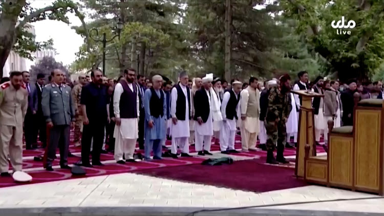 Afghanistan's President Ashraf Ghani (front row) attends Eid al-Adha prayers at the presidential palace, moments before the sounds of rocket explosions can be heard, in Kabul, Afghanistan, July 20, 2021, in this still image taken from TV footage.