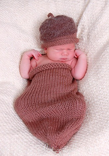 baby in acorn-themed cocoon and hat