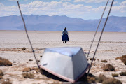 Cristina Mamani walks near an unused boat in Lake Poopo, Bolivia’s second largest lake, which has dried up due to water diversion for regional irrigation needs and a warmer climate, according to local residents and scientists. 