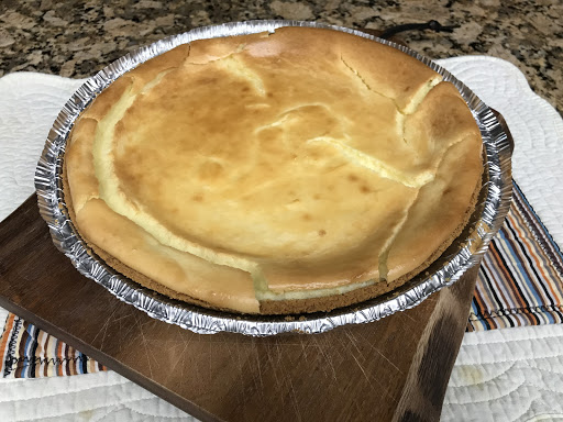 A baked cheesecake sitting on a wood cutting board. 