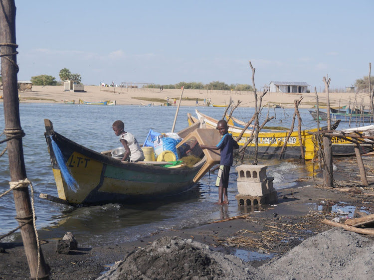 Turkana boys along the shores of Lake Turkana in Longech packing house goods to the boat after their homesteads were marooned by surging Lake Turkana.