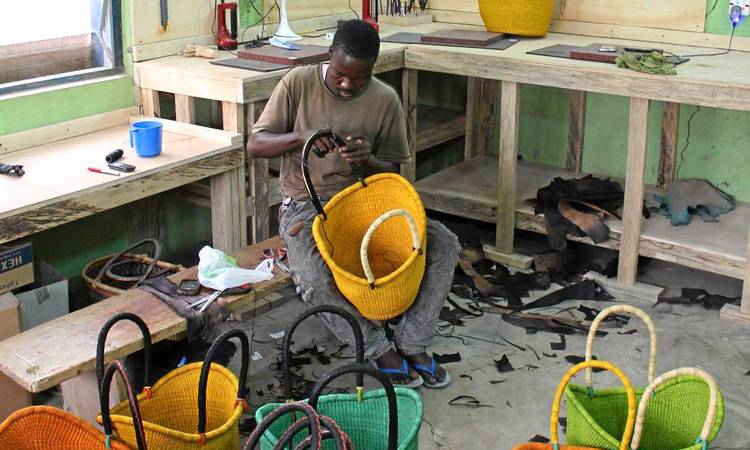 Weaver Adams Attiah applies goat leather to the handles of a 'dip-dyed Nyariga' baskets