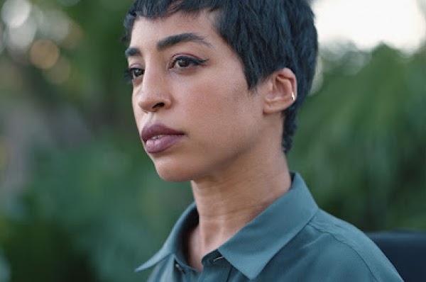 Jillian Mercado (ella), una mujer afrodescendiente discapacitada, usa una camisa verde azulado y mira a lo lejos