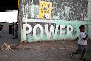 NEXUS: A young girl walks past an ANC election poster on a spaza shop in Florence Street,  in Duncan Village,  Eastern Cape.  The area is home to the very poor. Recent fires destroyed shacks just metres from the shop.