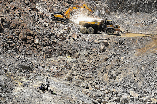 WARLORDS: Illegal miners work side by side with a mining company's articulated truck and excavator, removing rock near Benoni Gold Mine in Ekurhuleni. Residents of nearby New Modder were terrified on Sunday as rival gangs fought running battles over access to the gold reef