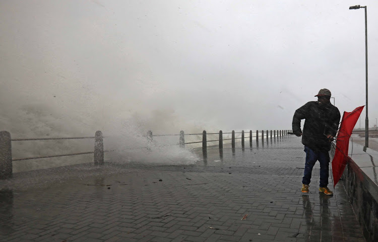 A man's umbrella suffers the consequences of the gale-force winds and heavy rainfall as a storm rages across the Sea Point promenade.