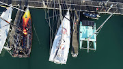 The catamaran uses a combination of sails, hydro-electric power and solar energy. Here it sits in the marina with the yacht, left, Norbert Koch intends to sail single-handedly around the world later this year.