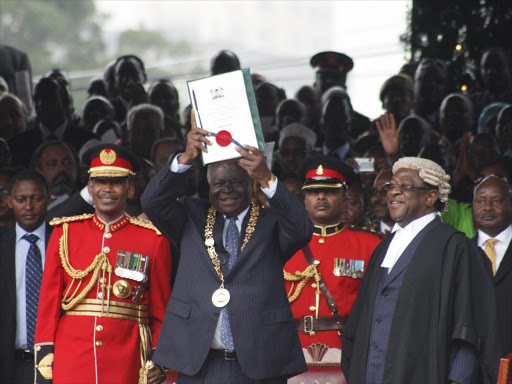 Retired President Mwai Kibaki shows off the new constitution with a national seals during the promulgation of the new constitution at Uhuru Park 27-8-10.He is flanked by former Attorney General Amos Wako Photo/ File