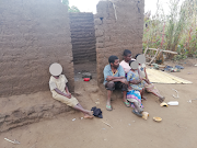 Cecilia Lapani, her husband Bizwick Lapani and three of their children sit in front of their old hut, which caused them stress that translated into less effective HIV treatment.