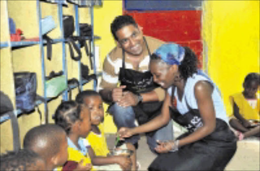 THRILLING DAY: Isidingo actors Hlubi Mboya and Jack Devnarian hand out food parcels from a fast food outlet to children at KwaMamami Day Care Centre in Orlando East, Soweto. Pic. Vathiswa Ruselo. 14/10/08. © Sowetan.