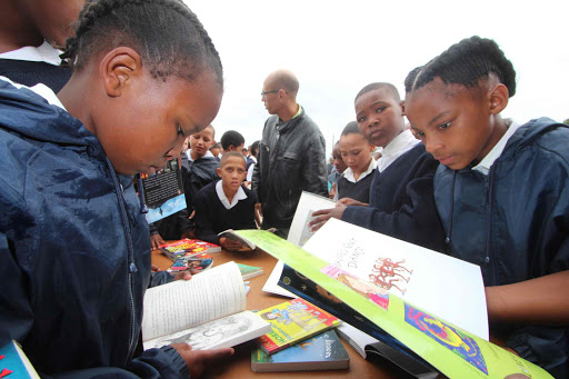 EAGER TO READ: Budding bookworms at Station Hill Primary page through some of the donated books yesterday after the community rallied together to open the facility at the school Picture: DAVID MACGREGOR