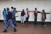 A police officer shows shoppers how to stand in a line.