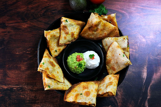 A platter of Chicken Quesadillas with guacamole and sour cream.