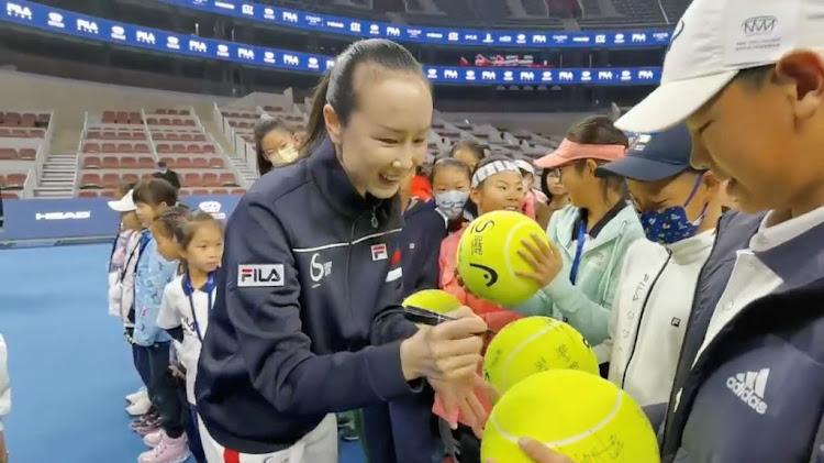 Chinese tennis player Peng Shuai signs large tennis balls at the opening ceremony of the Fila Kids Junior Tennis Challenger Final in Beijing on November 21 2021 in this screen grab obtained from a social media video.