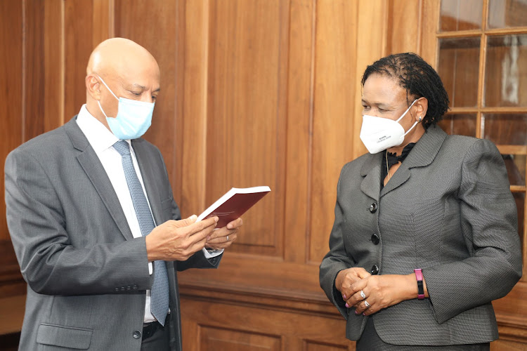 Chief Justice Martha Koome receives a casebook on money laundering and proceeds of crime from the chief executive officer of the Ethics and Anti-Corruption Commission Twalib Mbarak at her office.