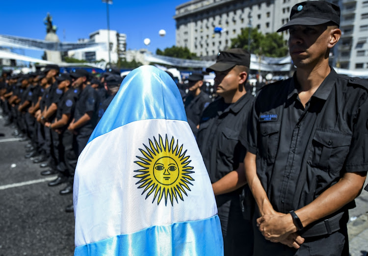 A protester wrapped in a flag stands in front of a line of police officers during a national strike against policies of President Javier Milei in Buenos Aires, Argentina, January 24 2024. Picture: MARCELO ENDELLI/GETTY IMAGES