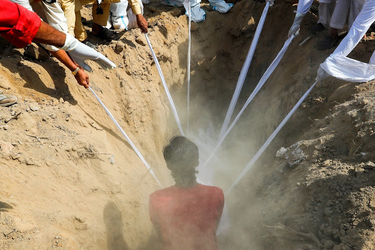 People lower the body of a man who died from Covid-19 into a grave in New Delhi.