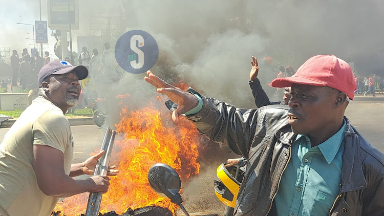 Protestors in Kondele, Kisumu look at a burning tyre ahead of Azimio la Umoja protest in Nairobi on March 20, 2023