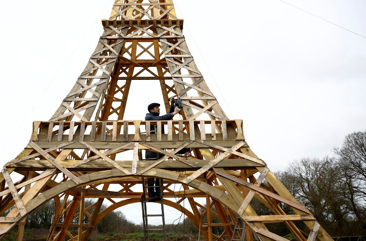 French carpenter Frederic Malmezac works on a 16-meter replica of the Eiffel Tower built from recycled wood.