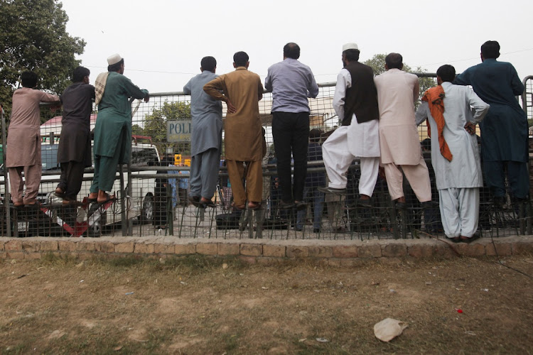 People climb on barriers along the route taken by former Prime Minister Imran Khan after he was discharged from Shaukat Khanum Memorial Cancer Hospital & Research Centre, in Lahore, Pakistan on November 6 2022. Picture: REUTERS/MOHSIN RAZA