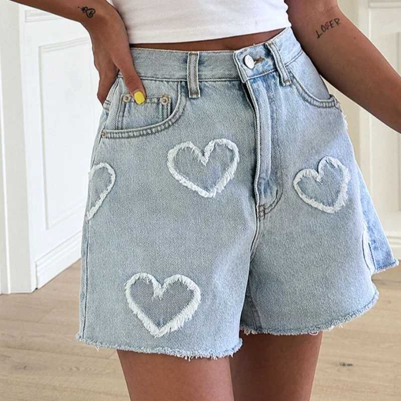 Shorts jeans de cintura alta com padrão de coração desfiado, cor clara e lavagem, perfeitos para looks leves e frescos no verão.