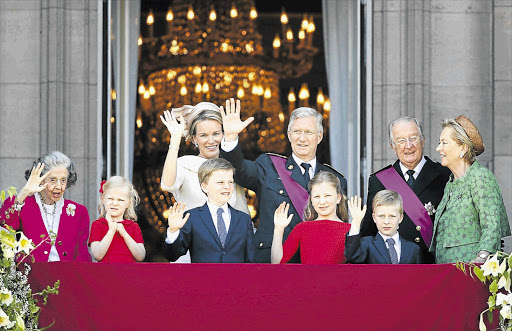 Belgium's new king, Philippe, and his queen, Mathilde, greet the crowds as the former king, Albert, and Queen Mother Paola, right, and Dowager Queen Fabiola and young princesses and princes, wave from a balcony of the royal palace in Brussels yesterday