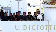 Migrants wait to disembark from the Italian coast guard vessel 