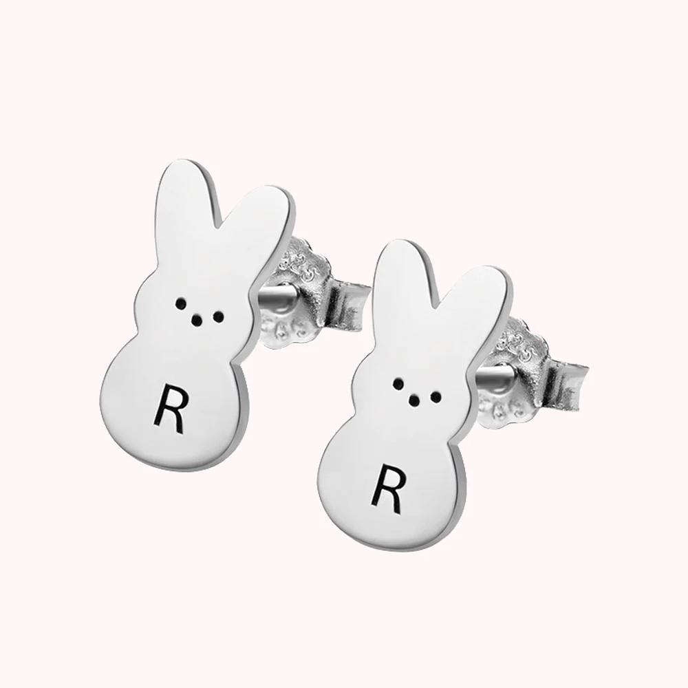 Boucles d’oreille en platine représentant un lapin de Pâques dont le ventre est personnalisé d’une initiale. 