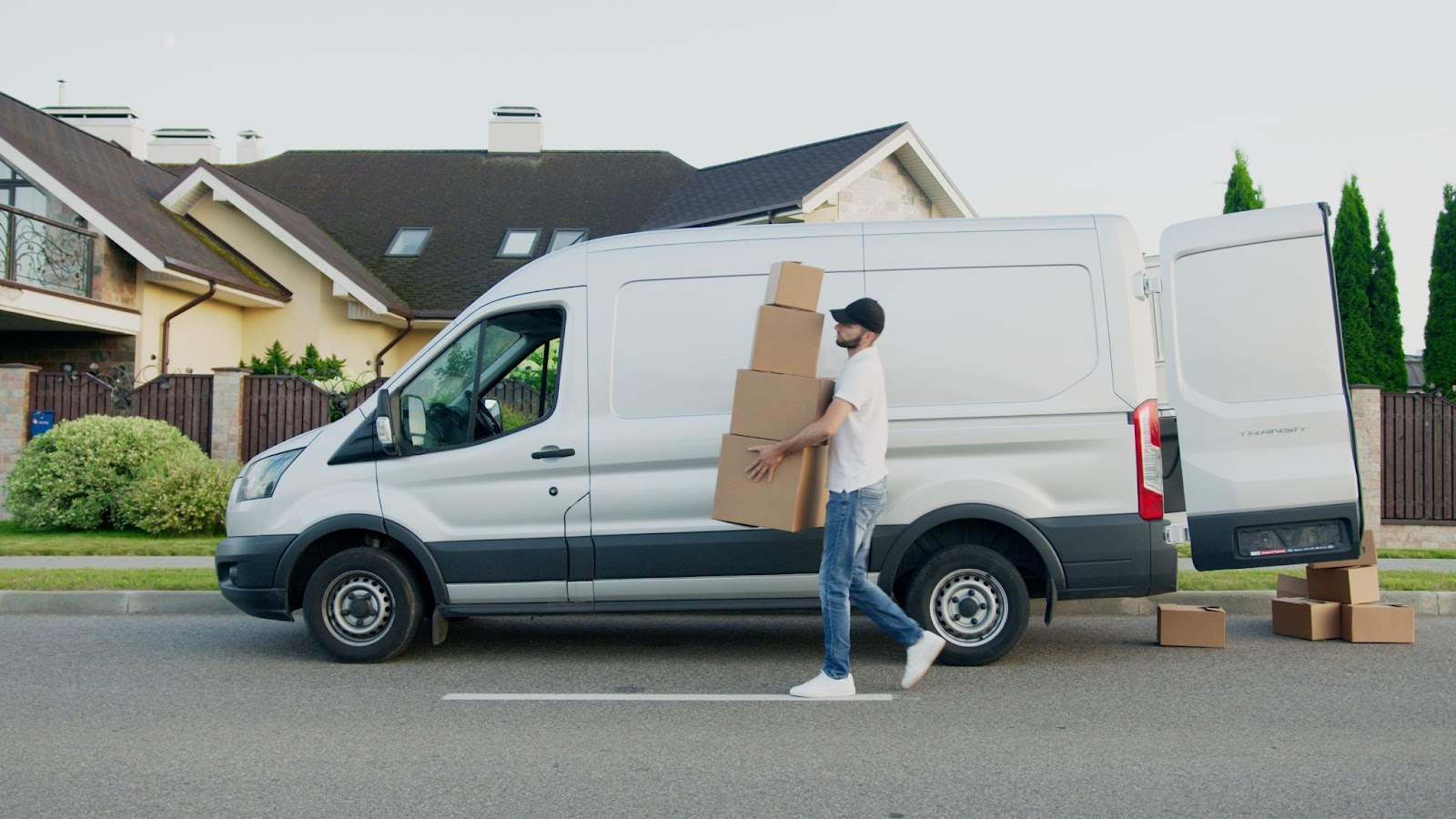 A panel truck with a man carrying boxes in front of the side profile of the truck