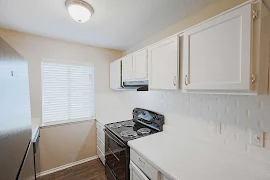 Galley style kitchen with white cabinets, white tile backsplash, white countertops, and wood inspired flooring