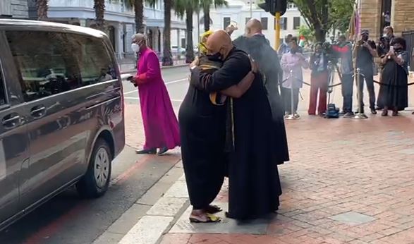 Archbishop Emeritus Desmond Tutu's widow, Leah, embraces the dean of St George's Cathedral in Cape Town, the Rt Rev Michael Weeder, after arriving with her husband's coffin on December 30 2021.