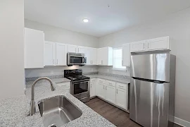 Kitchen with stone countertops, stainless steel appliances, and white cabinets with recessed lighting above 