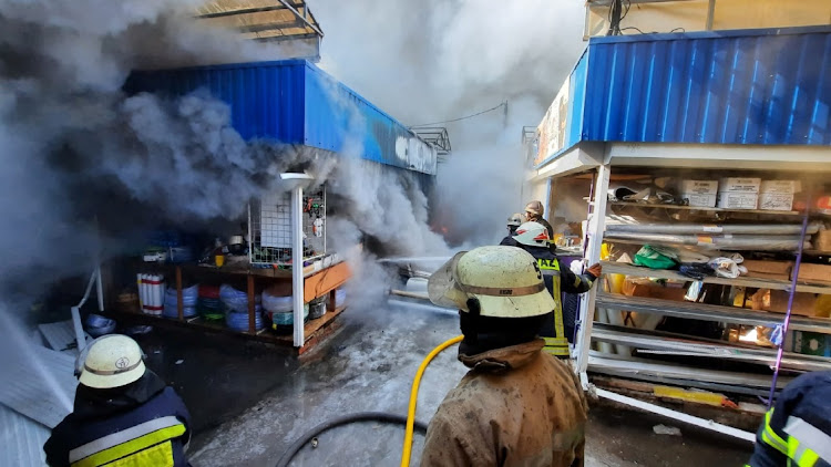 Rescuers work next to a household market damaged by shelling, as Russia's invasion of Ukraine continues, in Kharkiv, Ukraine, in this handout picture released March 16 2022. Picture: REUTERS/STATE EMERGENCY SERVICE