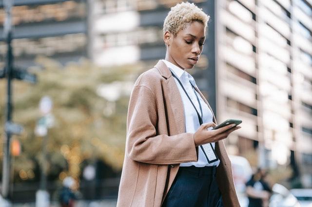 A lady holding her phone in front of a storey building