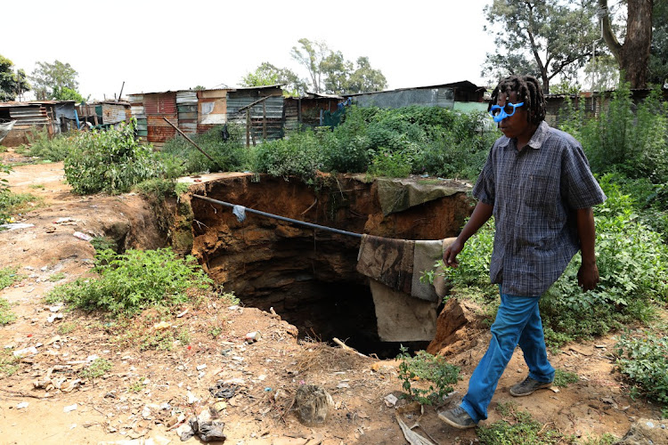 Jabu, a resident of Angelo informal settlement in Ekurhuleni walks past a sinkhole.