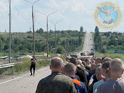 A man with a white flag walks on a road during an exchange of prisoners, as Russia's attack on Ukraine continues, in the location given as Zaporizhzhia, Ukraine, in this handout photo released on June 29, 2022.   