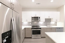 Kitchen with textured backsplash, neutral cabinets, white quartz countertops, and stainless steel appliances