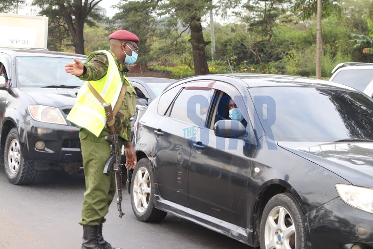 General Service Unit (GSU) officers monitor vehicles as they secure a checkpoint meant to indicate border of Kiambu and Murang'a counties in BluePost area, Thika on March 27, 2021