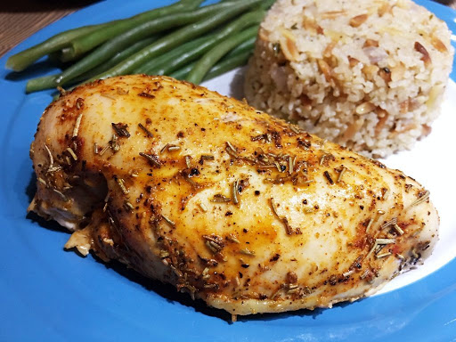 Grilled chicken on a plate along with rice and green beans.
