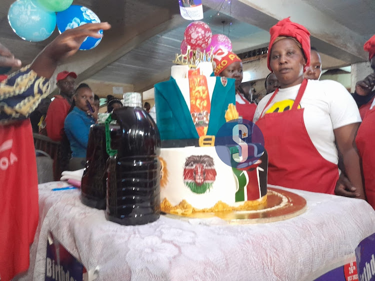 A trader in Gatundu constituency posing with a cake baked for Retired President Uhuru Kenyatta's birthday on October 26, 2023