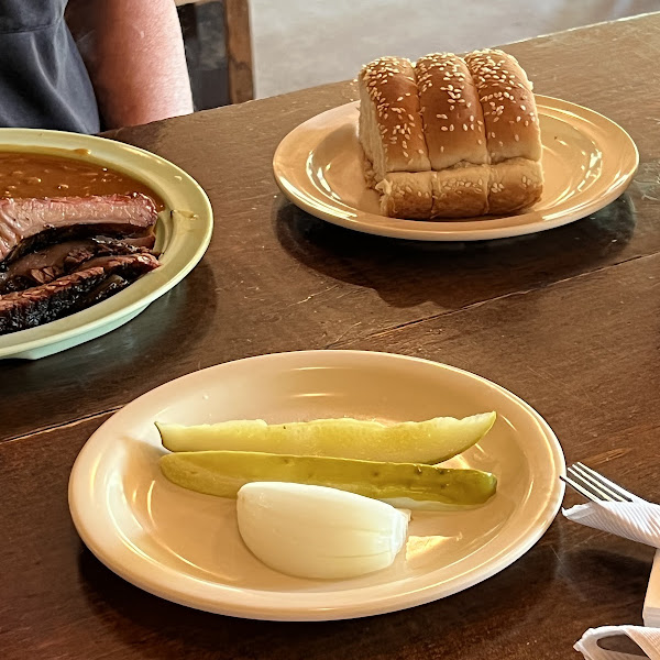 Pickle and onion on one plate, bread served separately from all other food on another plate