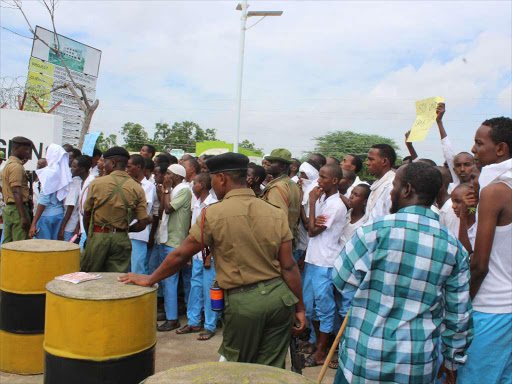 police keep vigil outside the provincial headquarters as students of Garissa high school wave placards to protest alleged grabbing of part of their school land by a private developer.