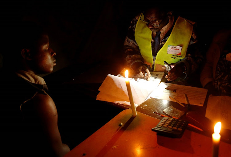 An election official assists a voter during the country's general elections in Chegutu, Zimbabwe, July 30, 2018.