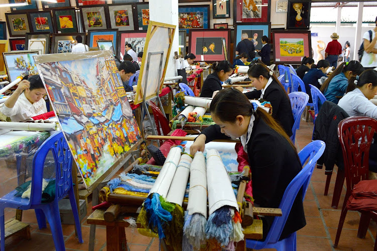 Students create paintings at an art studio. Many of the artists have disabilities — some of them were victims of napalm bombing by the U.S. during the Vietnam War.