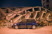 A car parks next to a collapsed building in the city of Adıyaman in Türkiye 