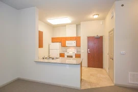 View of entry and kitchen area including kitchen peninsula with breakfast bar, wood cabinets, white appliances