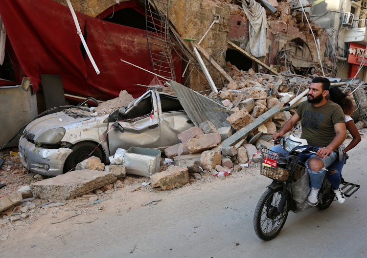 A man rides on a motorbike near rubble from damaged buildings after Tuesday's huge blast in Beirut's port area that killed at least 145 people and injured 5,000. President Michel Aoun blamed the blast on 2,750 tonnes of ammonium nitrate, used in fertilisers and bombs, that had been stored for six years at the port after it was seized