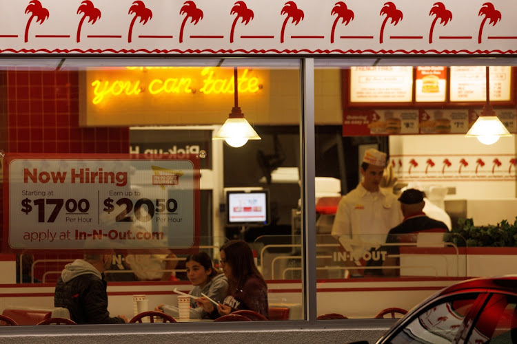 "Now hiring" sign is displayed on the window of an IN-N-OUT fast food restaurant in Encinitas, California.