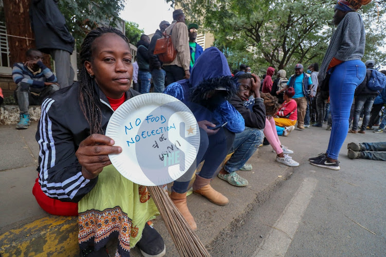 A woman holds a plate labeled the expected prices of household commodities during a protest outside the State Law office and department of Justice along Harambee Avenue Nairobi on July 7, 2022 during the annual Saba Saba protest.